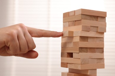 Photo of Playing Jenga. Man building tower with wooden blocks indoors, closeup
