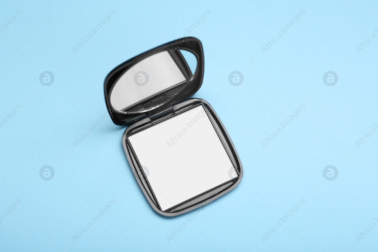 Photo of Stylish cosmetic pocket mirror on light blue background, top view