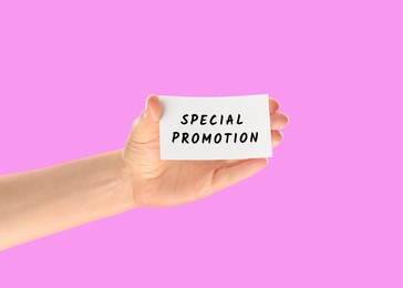 Image of Woman holding card with text Special Promotion on pink background, closeup