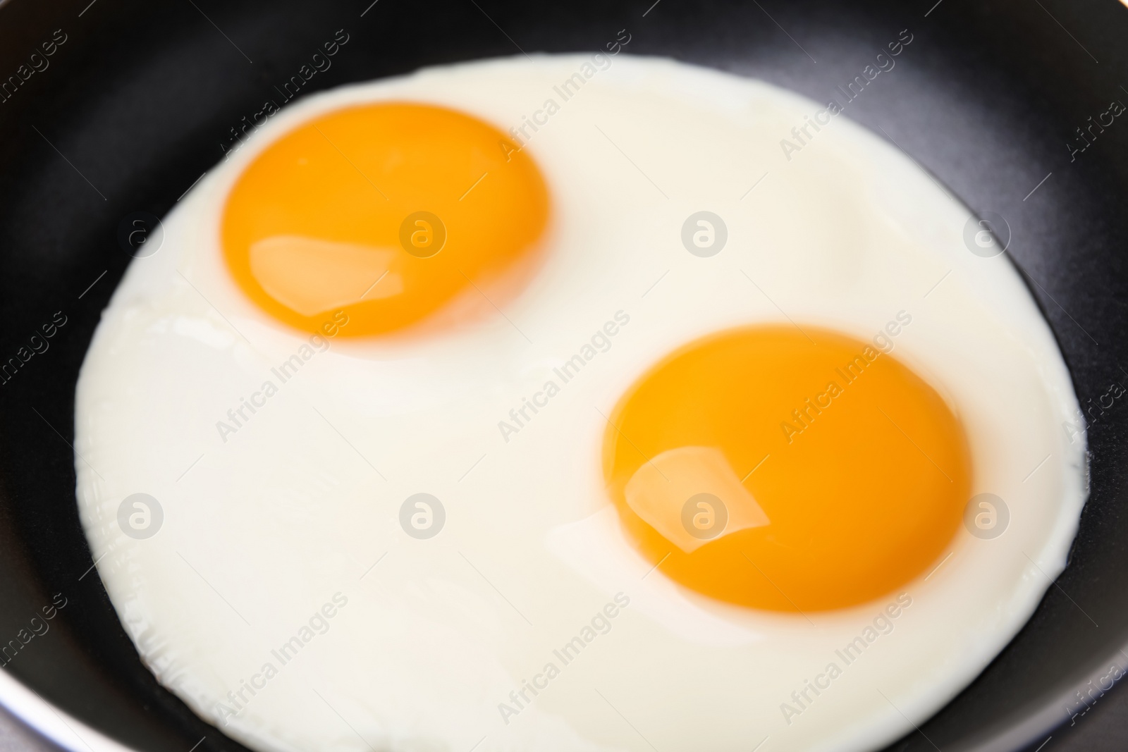 Photo of Tasty fried eggs in pan, closeup view