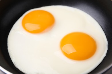 Tasty fried eggs in pan, closeup view