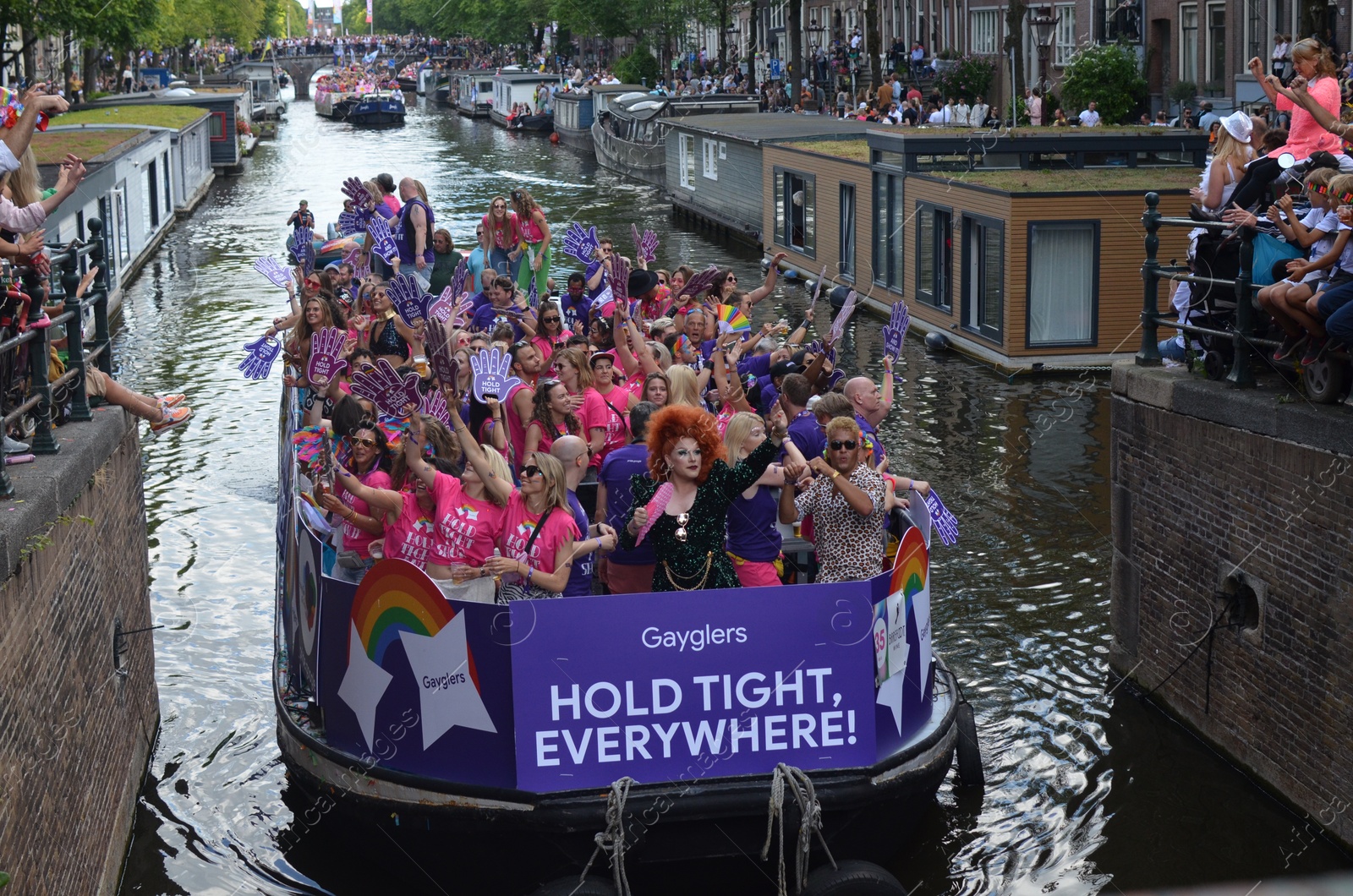 Photo of AMSTERDAM, NETHERLANDS - AUGUST 06, 2022: Many people in boats at LGBT pride parade on river