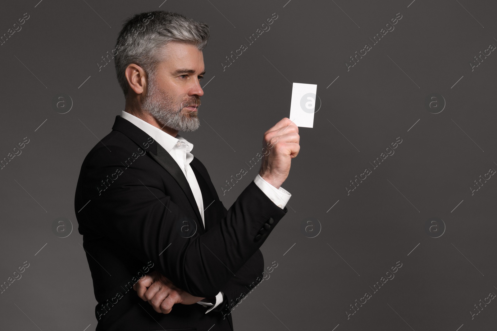 Photo of Handsome businessman holding blank business card on grey background. Space for text