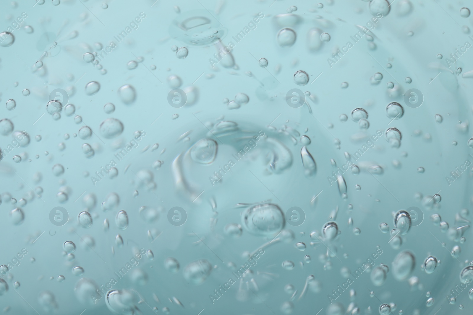 Photo of Pure transparent cosmetic gel on light blue background, closeup