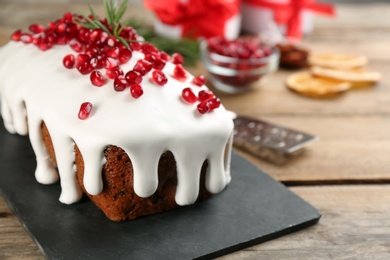 Traditional classic Christmas cake decorated with pomegranate seeds and rosemary on wooden table