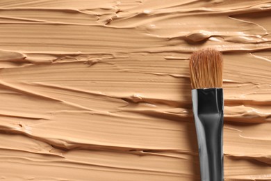 Photo of Skin foundation and makeup brush as background, closeup