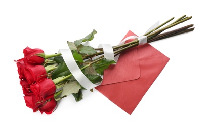 Beautiful red roses and envelope on white background, top view. St. Valentine's day celebration