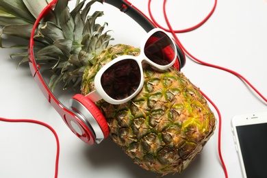 Photo of Pineapple with headphones and sunglasses on white background
