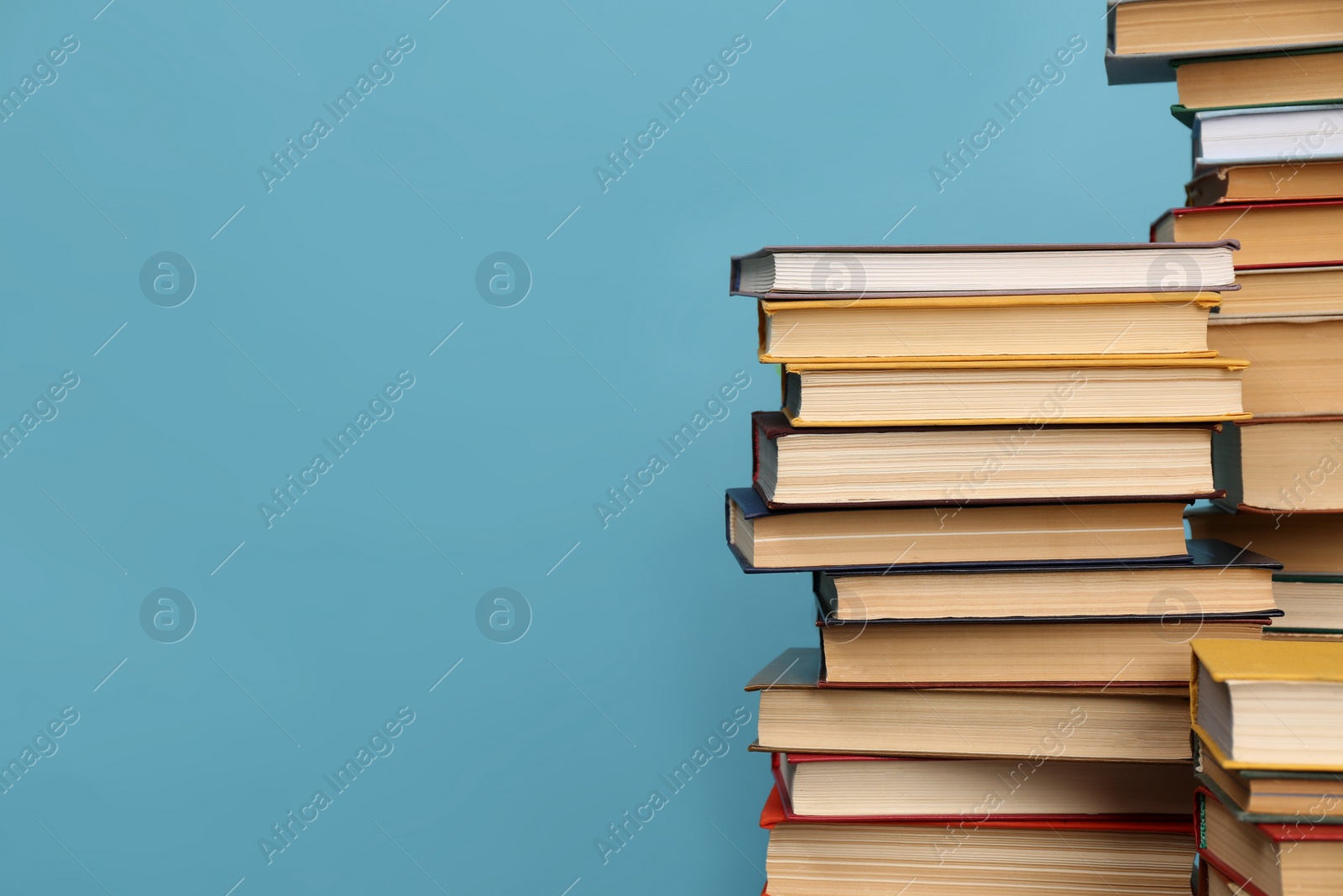 Photo of Many hardcover books on turquoise background, space for text. Library material