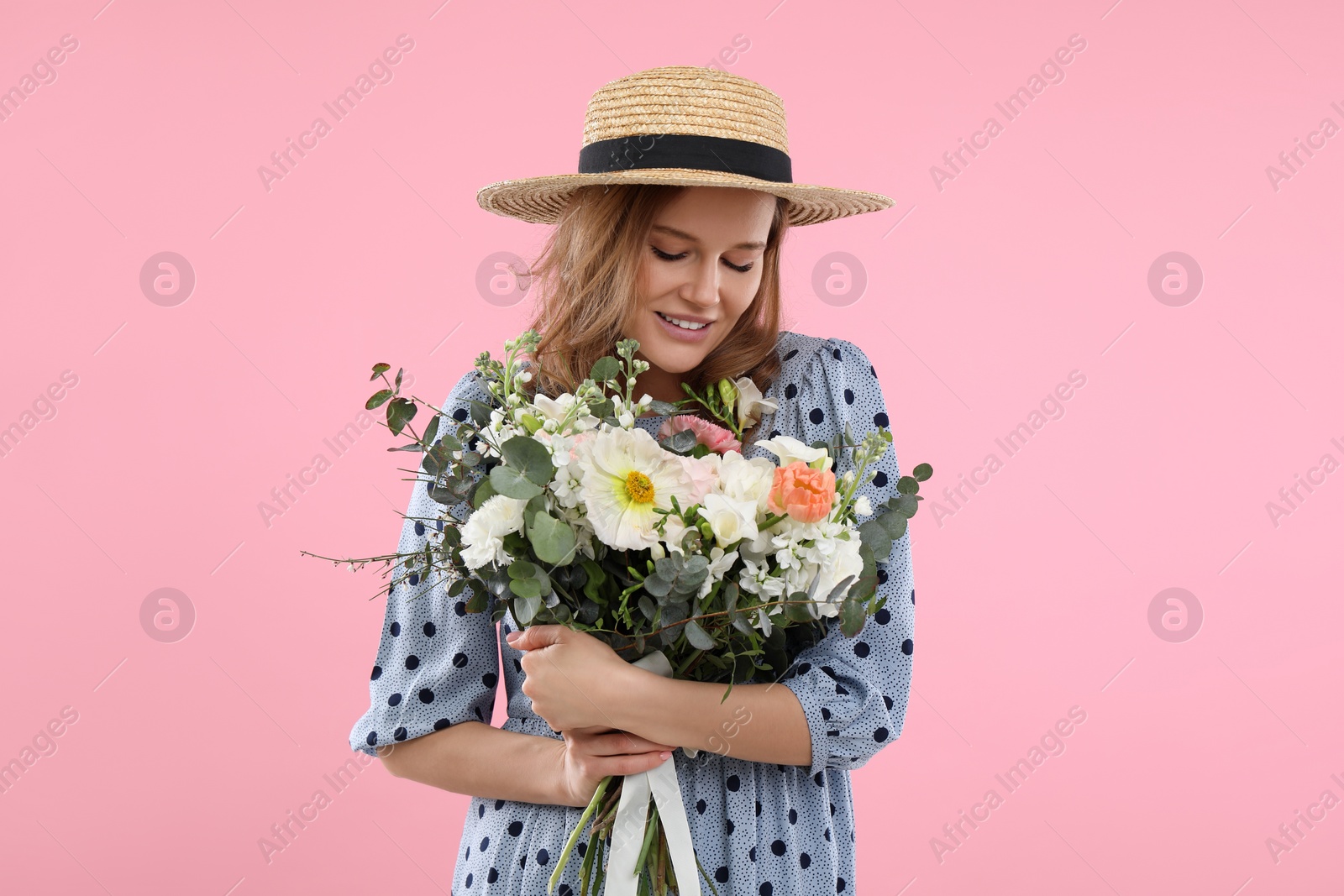 Photo of Beautiful woman in straw hat with bouquet of flowers on pink background