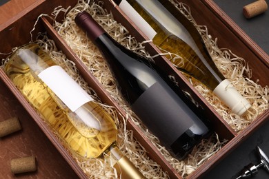 Box with wine bottles on dark table, top view