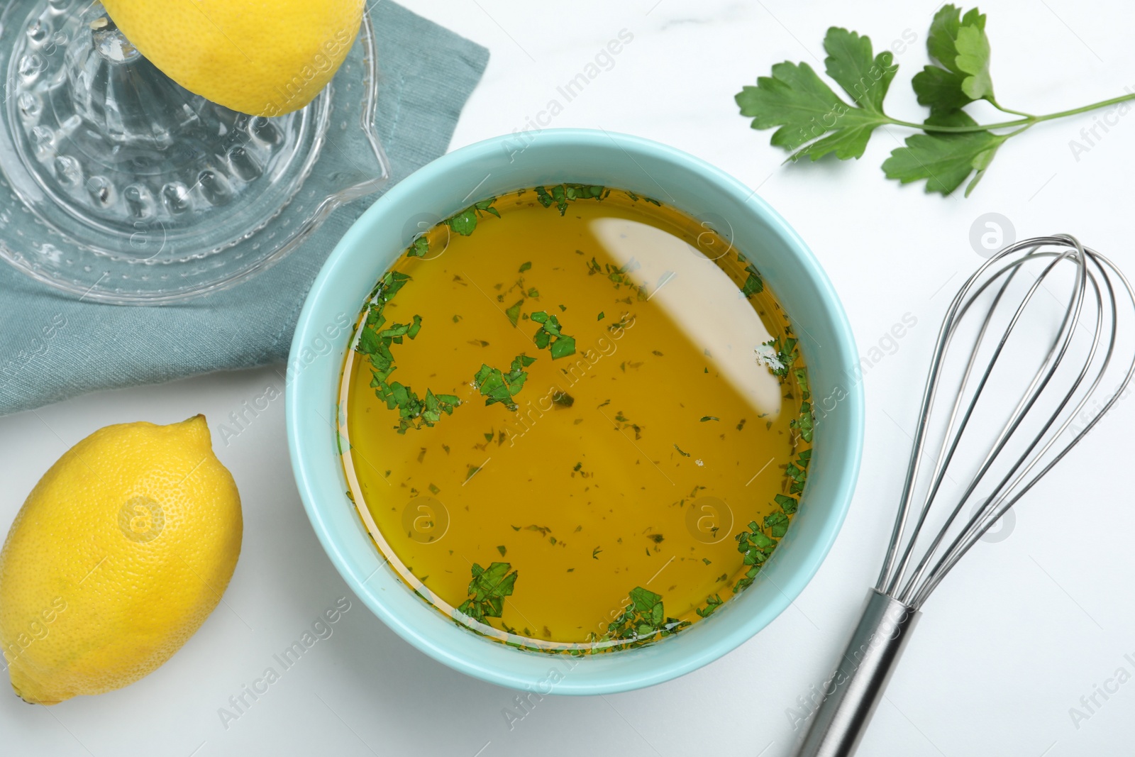 Photo of Bowl with lemon sauce on white table, flat lay. Delicious salad dressing