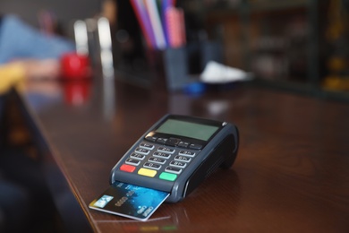 Photo of Credit card machine for non cash payment on wooden counter in cafe. Space for text