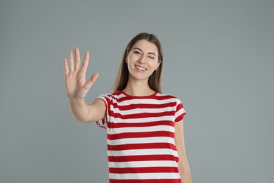 Photo of Woman showing number five with her hand on grey background