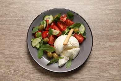 Delicious burrata salad on wooden table, top view