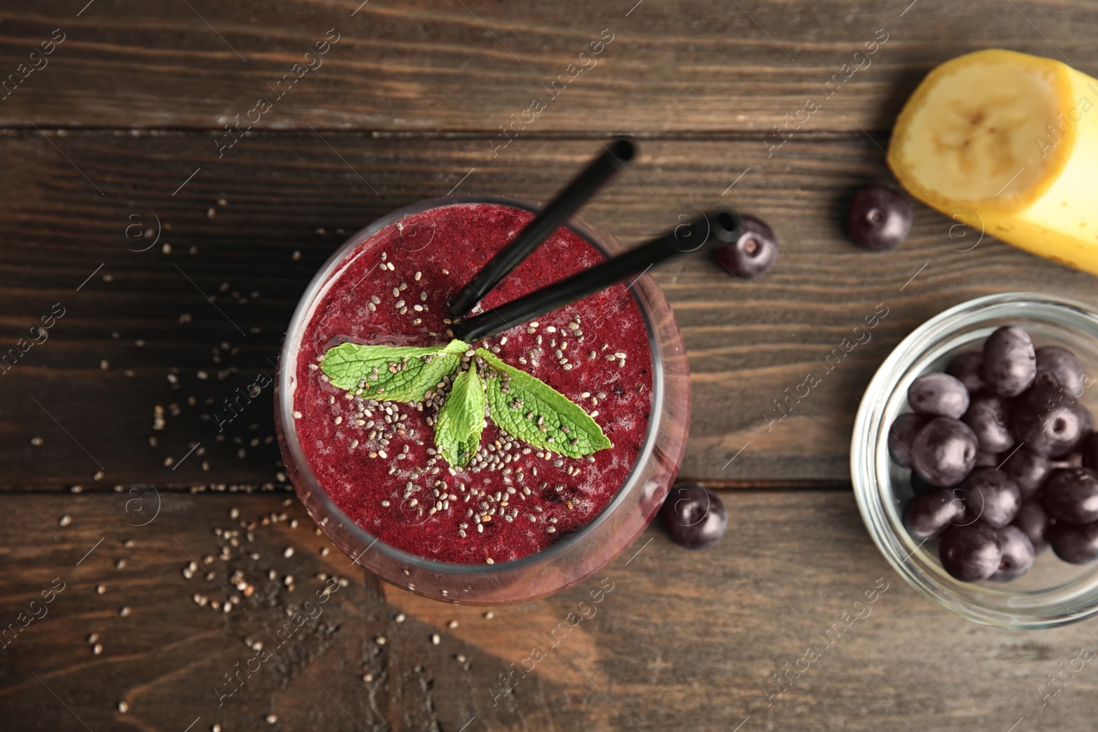 Photo of Glass with delicious acai smoothie on wooden table, top view