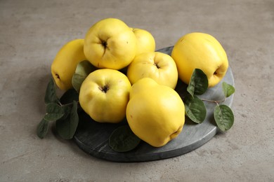 Photo of Fresh ripe organic quinces with leaves on grey table