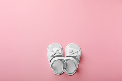 Pair of cute baby sandals on color background, top view