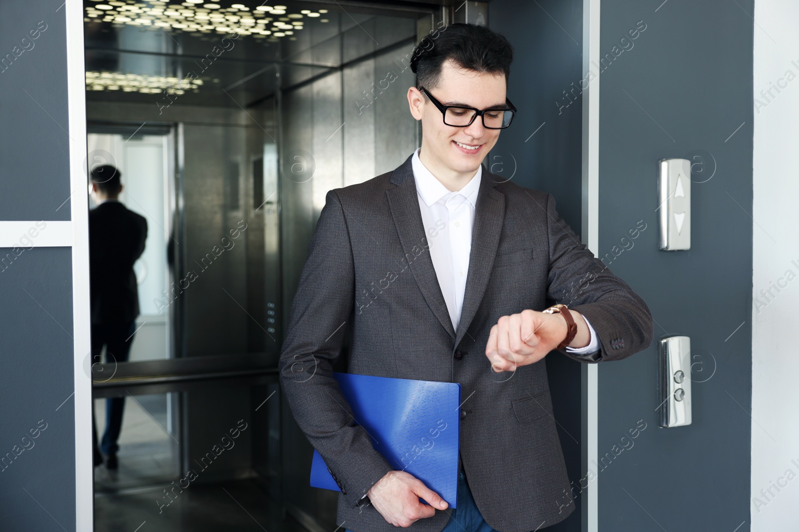 Photo of Young businessman walking out of modern elevator