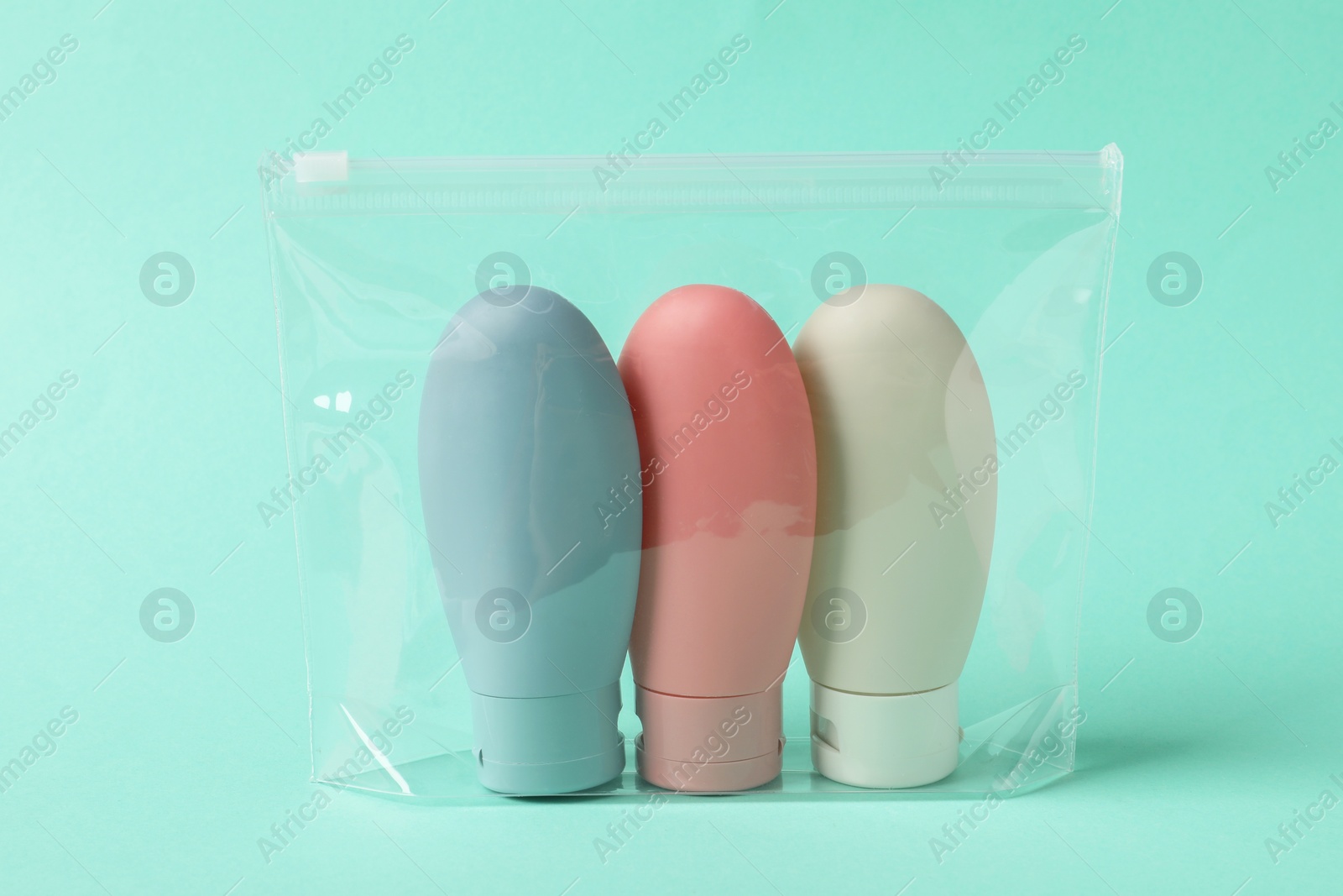 Photo of Cosmetic travel kit in plastic bag on turquoise background. Bath accessories