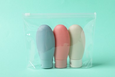 Photo of Cosmetic travel kit in plastic bag on turquoise background. Bath accessories