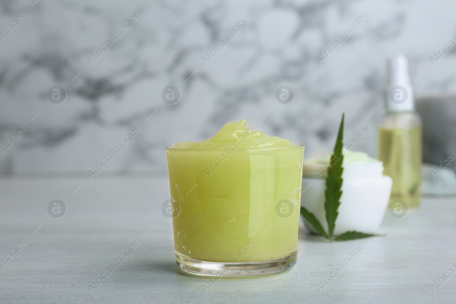 Photo of Glass of moisturizing hemp lotion on table