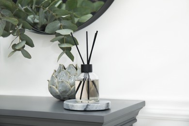 Photo of Reed diffuser and home decor on grey table near white wall