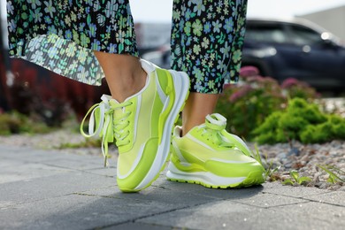 Woman wearing pair of stylish sneakers outdoors, closeup