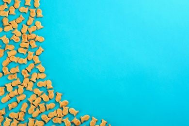 Delicious goldfish crackers on blue background, flat lay. Space for text