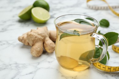 Photo of Diet herbal tea with green leaves and ginger on white marble table