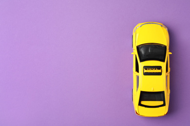 Photo of Yellow taxi car model on purple background, top view. Space for text