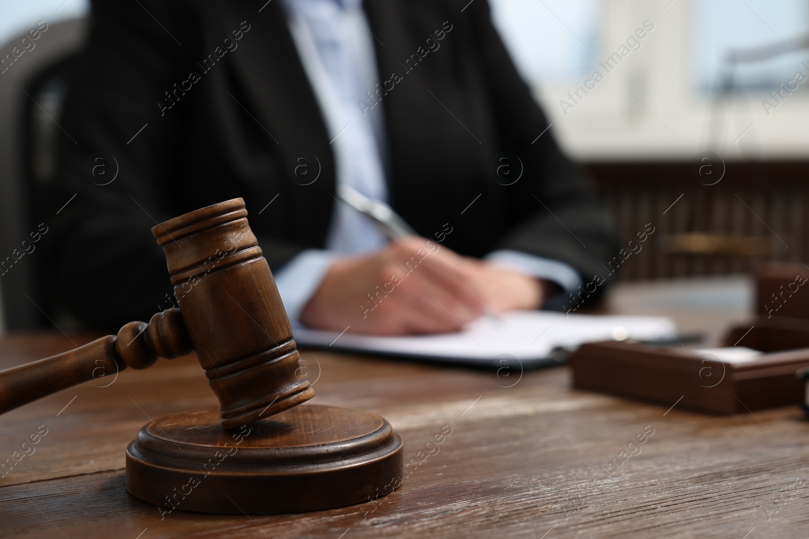 Photo of Lawyer working at wooden table in office, focus on gavel