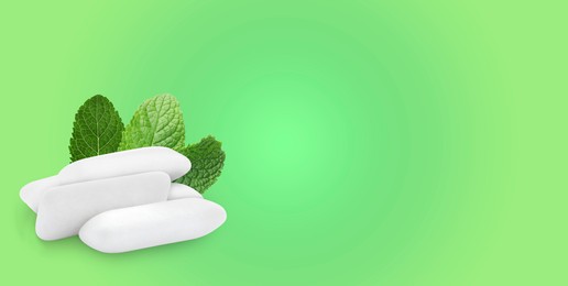 Menthol chewing gum pillows and mint leaves on light green gradient background, space for text. Banner design