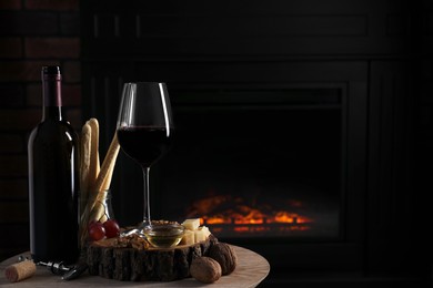 Photo of Glass of red wine and snacks on wooden table indoors. Space for text