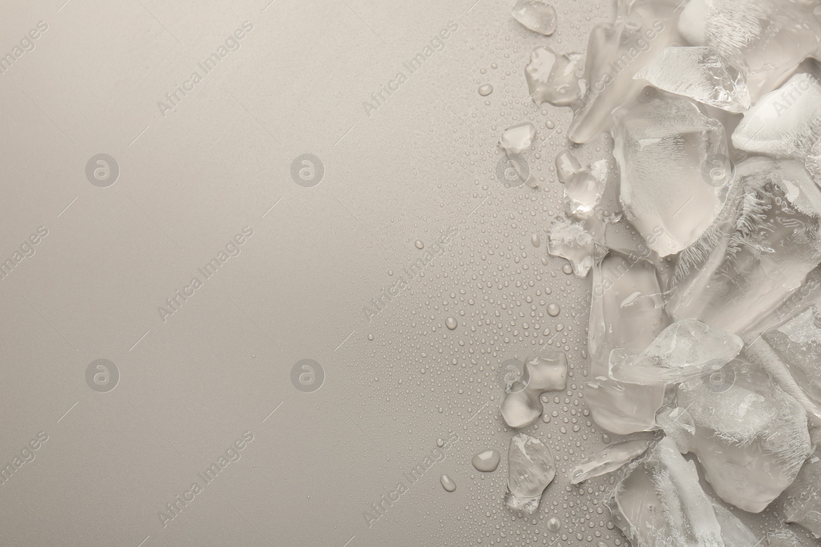 Photo of Pieces of crushed ice on grey background, top view. Space for text