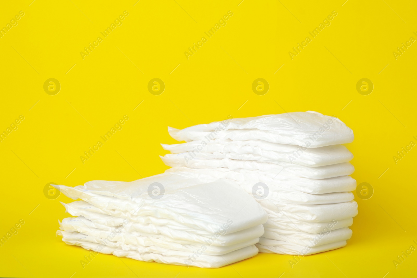 Photo of Stacks of baby diapers on yellow background