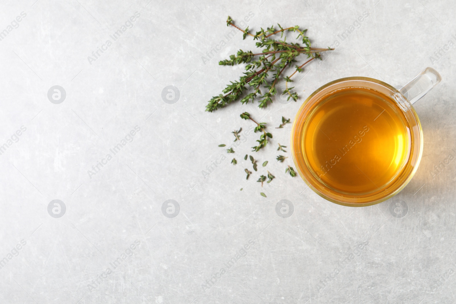 Photo of Aromatic herbal tea with thyme on light grey table, flat lay. Space for text