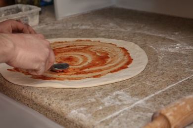 Photo of Man preparing pizza at table, closeup. Oven recipe