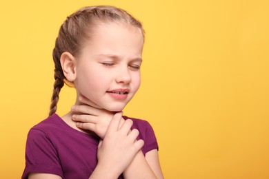 Girl suffering from sore throat on orange background. Space for text