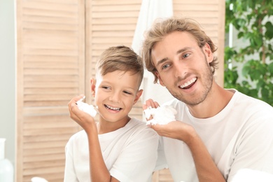 Photo of Father and son applying shaving foam in bathroom