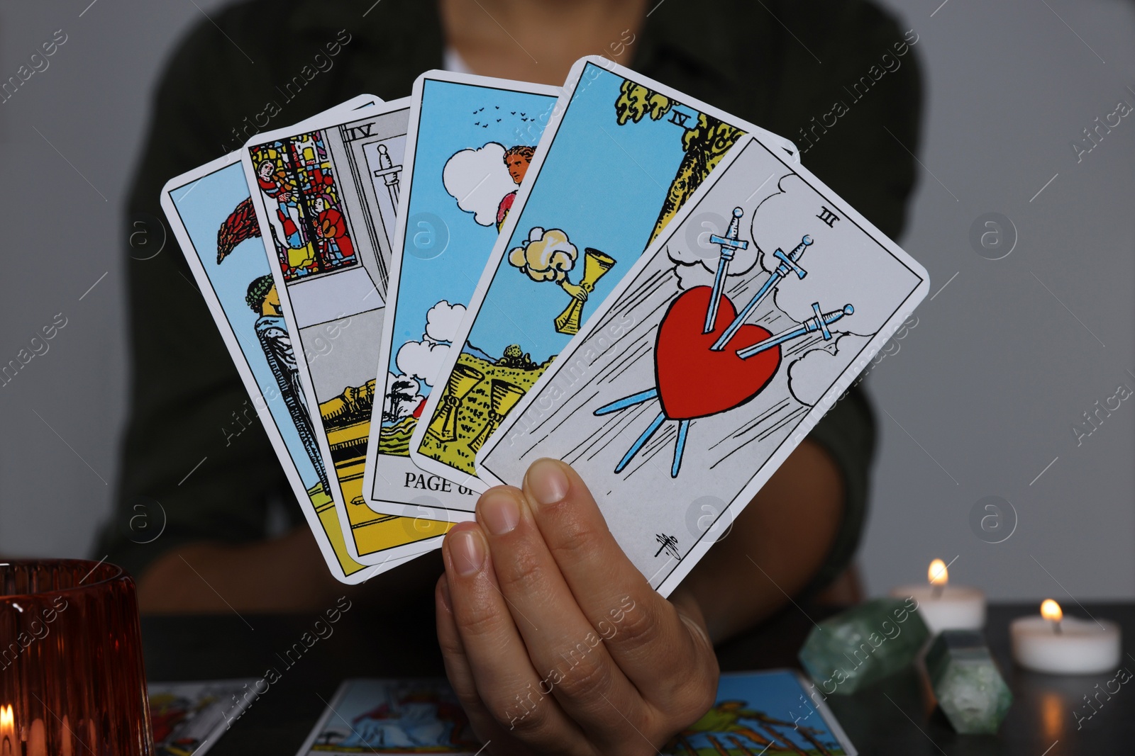 Photo of Fortune teller with tarot cards at grey table indoors, closeup