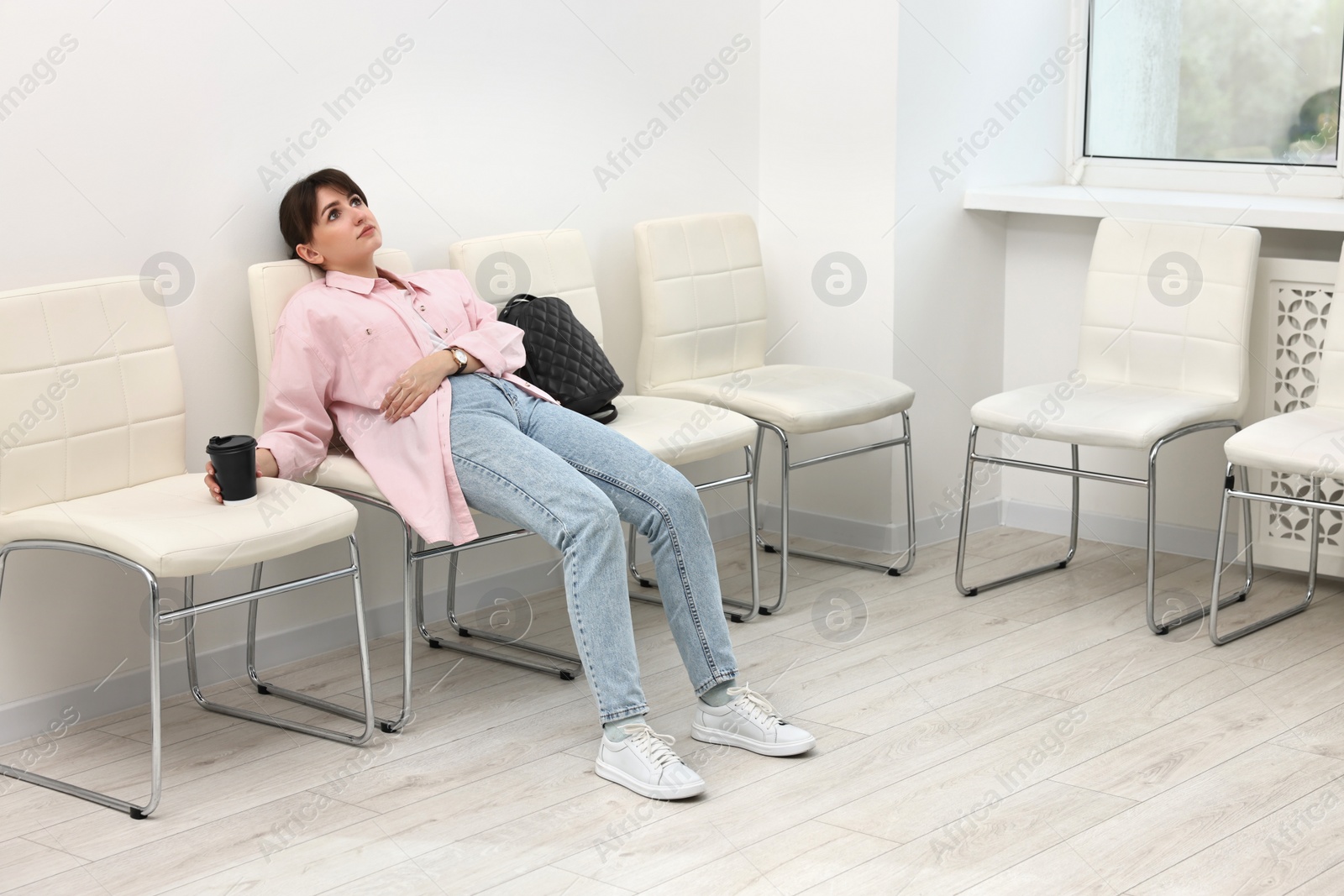 Photo of Tired woman sitting on chair and waiting for appointment indoors