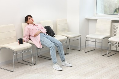 Photo of Tired woman sitting on chair and waiting for appointment indoors