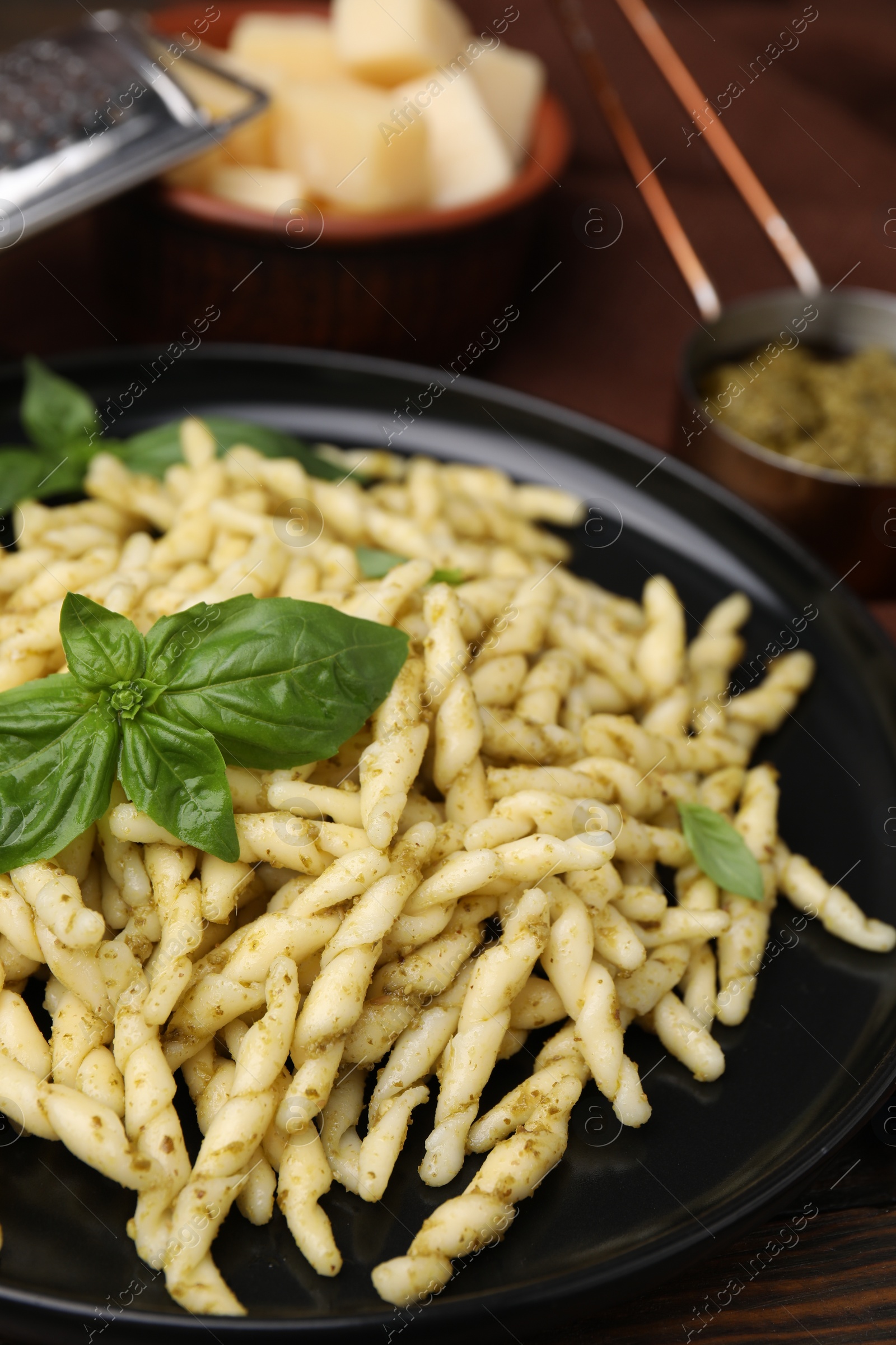 Photo of Plate of delicious trofie pasta with pesto sauce and basil leaves on table, closeup