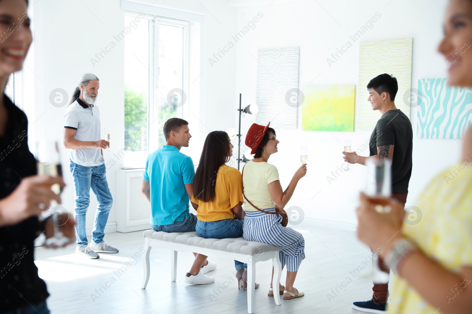 Photo of Group of people with glasses of champagne at exhibition in art gallery