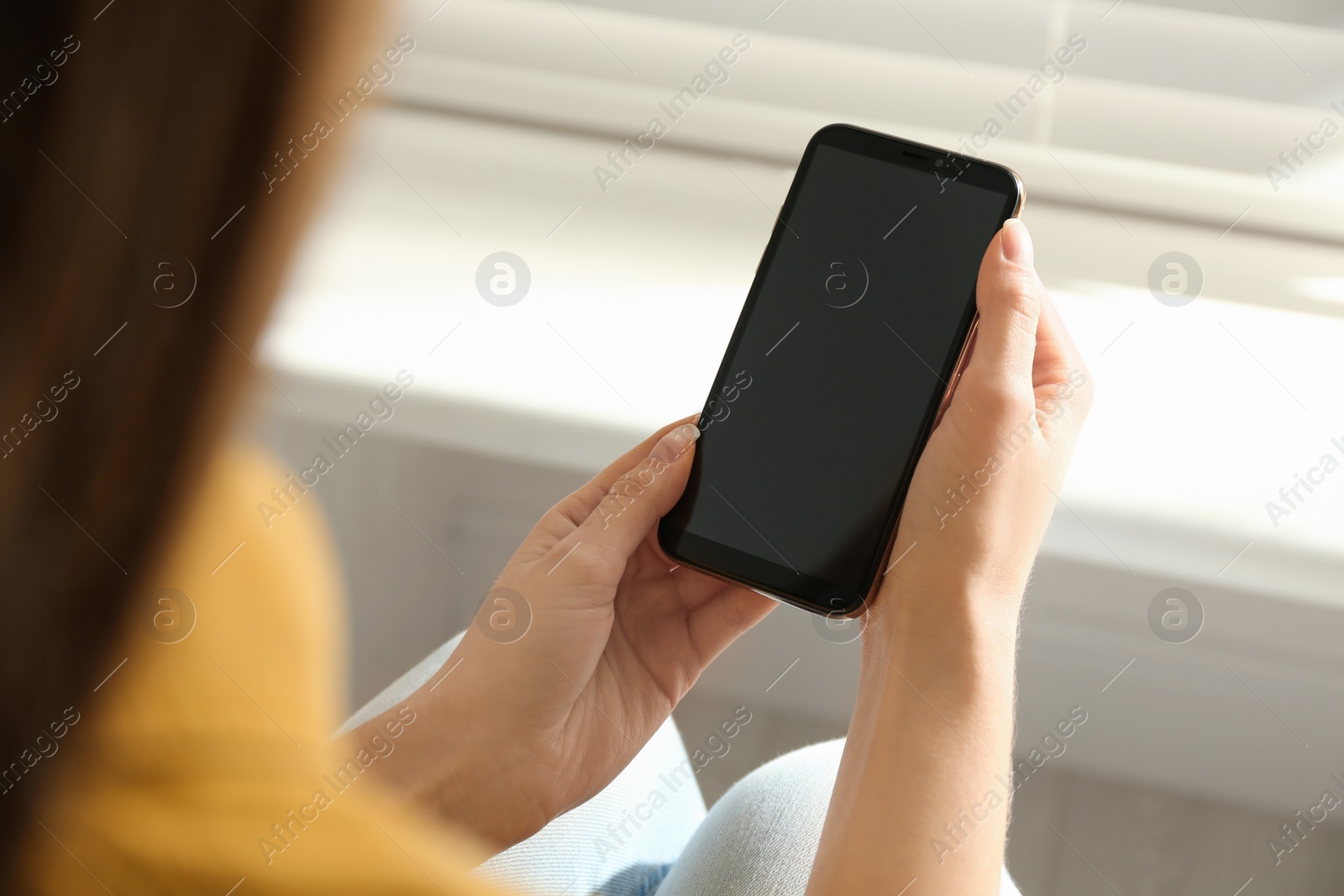 Photo of Young woman using modern smartphone indoors, closeup