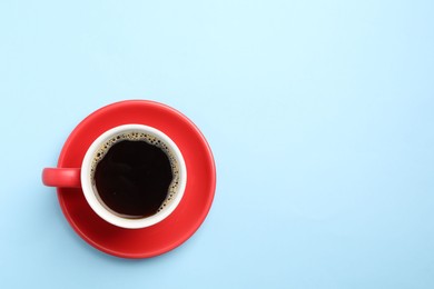 Photo of Aromatic coffee in cup on light blue background, top view. Space for text