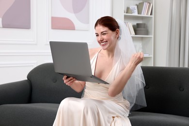 Photo of Cheerful bride with laptop in living room