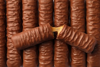 Photo of Sweet tasty chocolate bars with caramel as background, top view