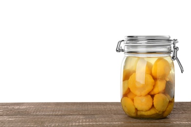 Jar of pickled custard squashes on wooden table against white background. Space for text